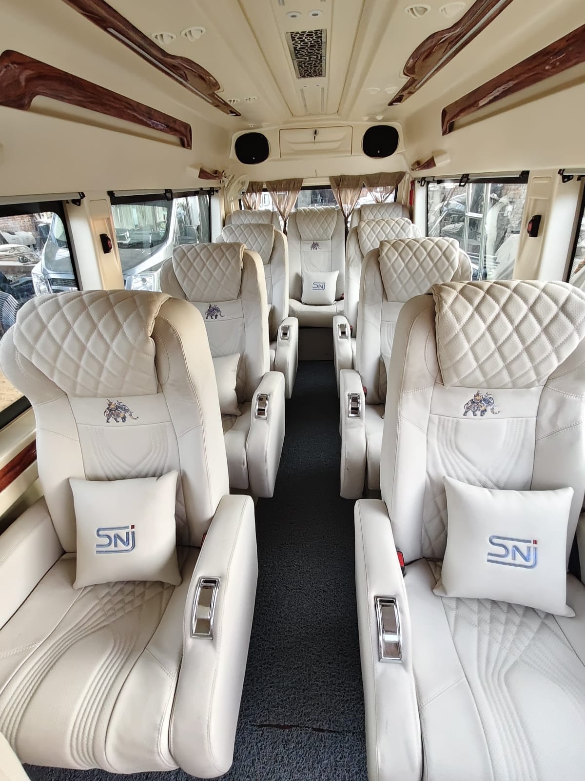 Cream leather recliner seats inside a luxury Sri Subramanyaswamy Tempo Traveller